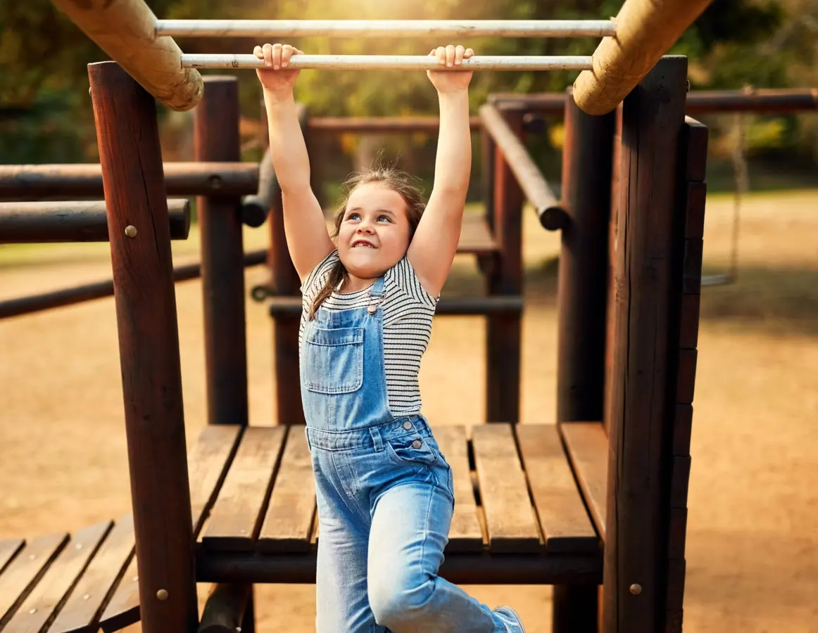 A child climbs on playground equipment outdoors.
