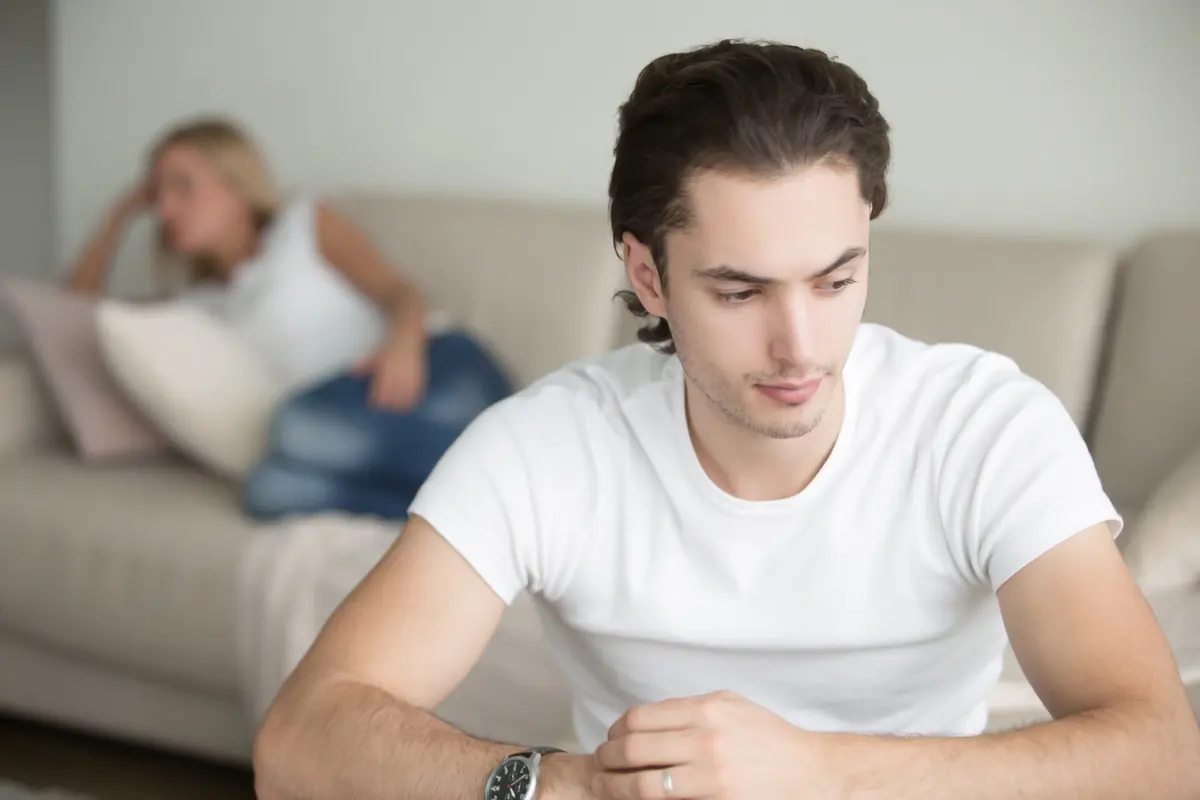 A young person looks at a phone while others sit nearby.