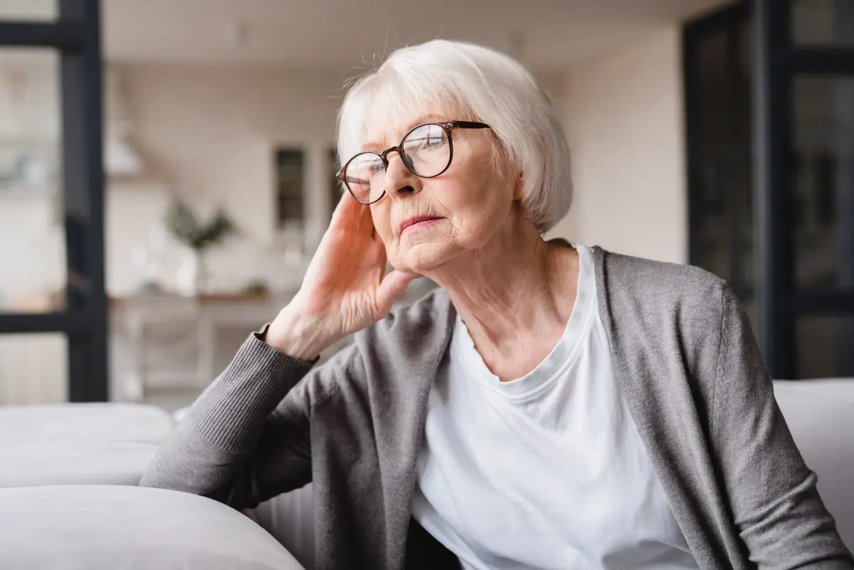 An older woman takes a quiet moment while seated at home.