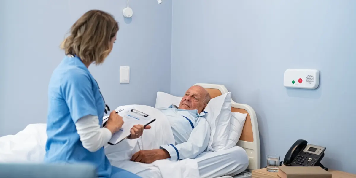 A healthcare professional checks on an older patient in a medical room.
