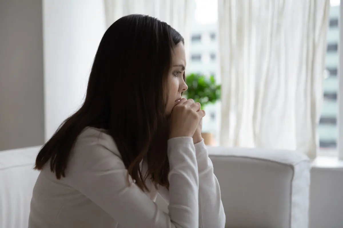 A woman takes a quiet moment beside a window.