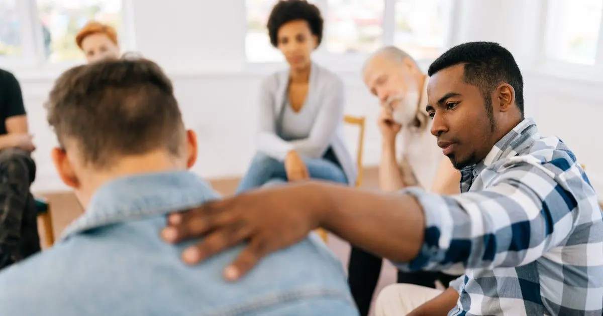 A person offers a reassuring touch during a small group conversation.