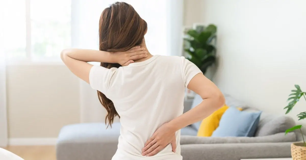 A woman stretches her shoulders and lower back at home.