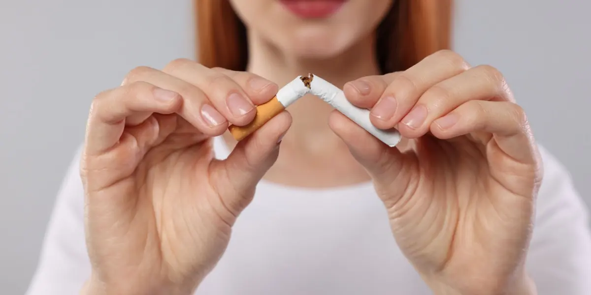 Hands break a cigarette in half.