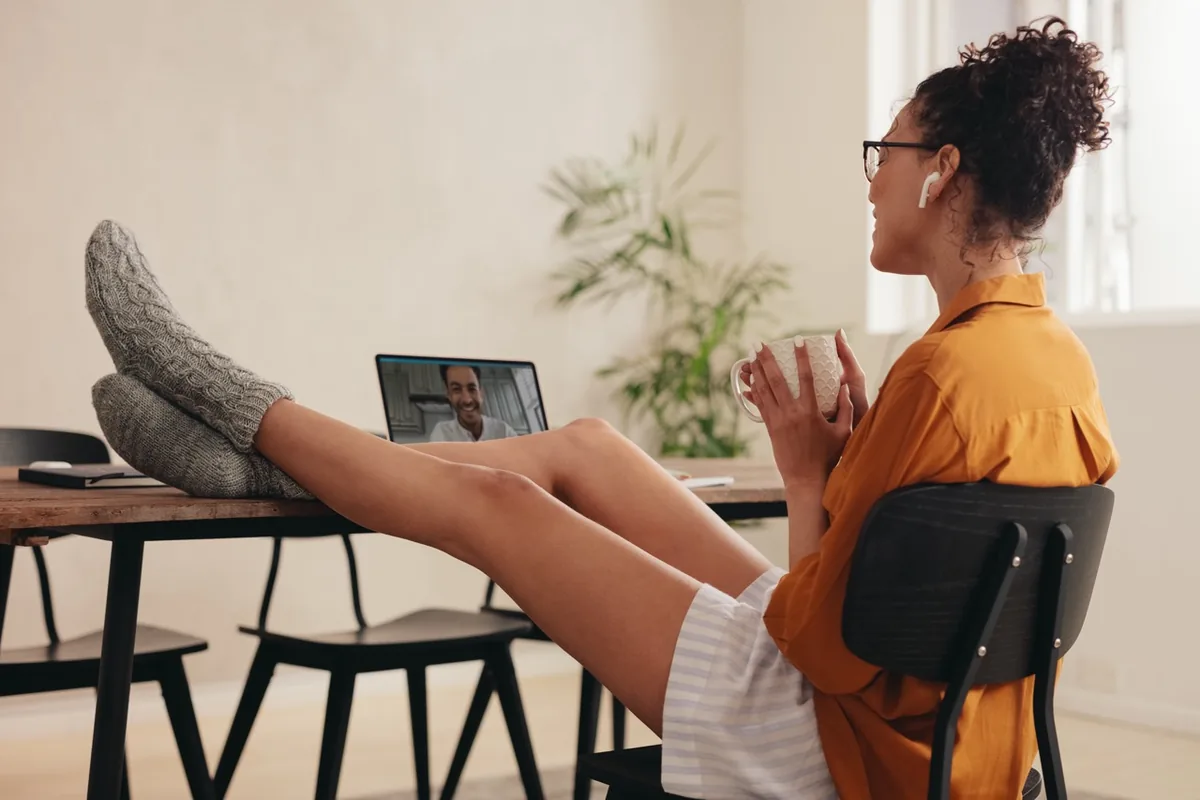 A woman speaks with someone on a tablet from her living room.