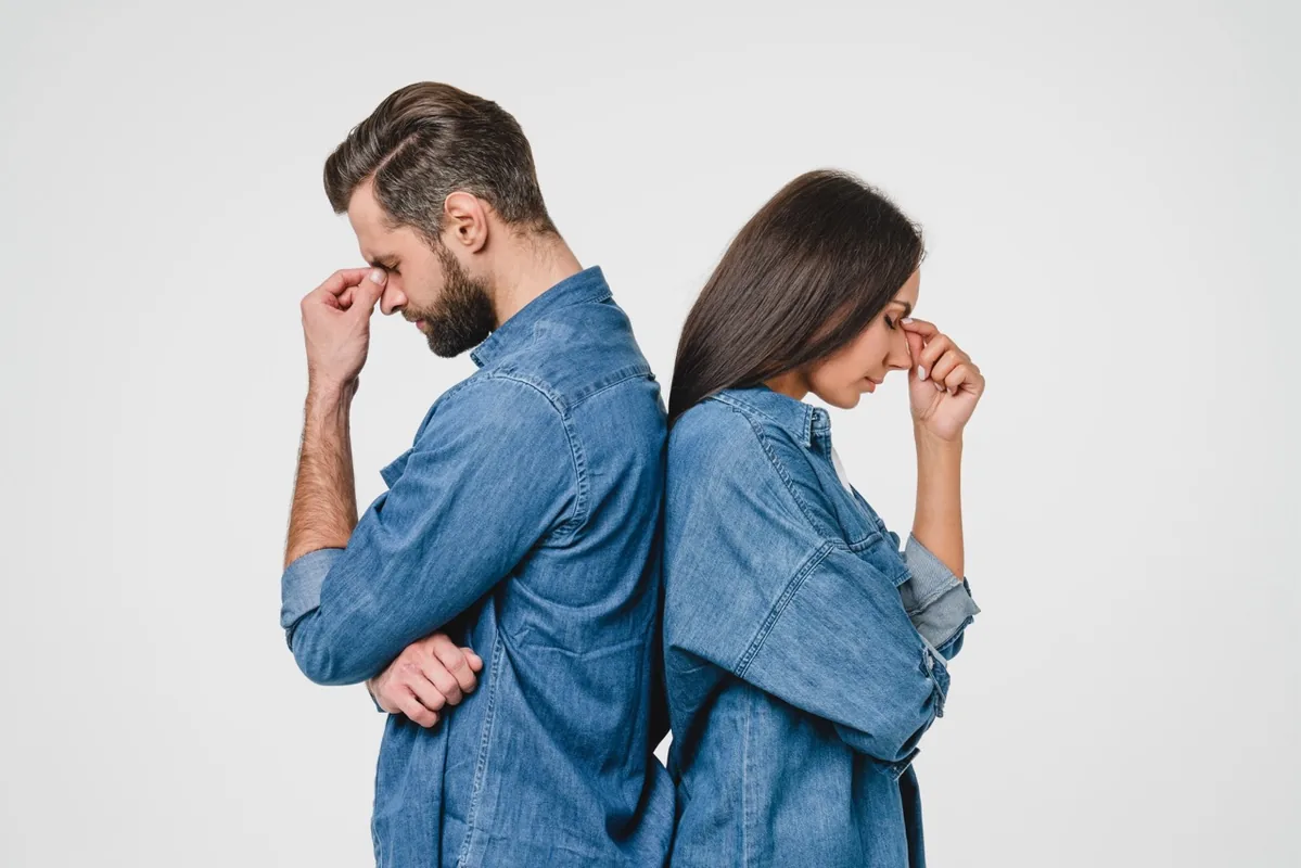 Two people stand back to back, each deep in thought.