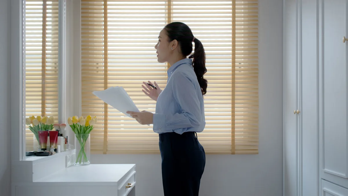 A woman rehearses a presentation beside an office window.