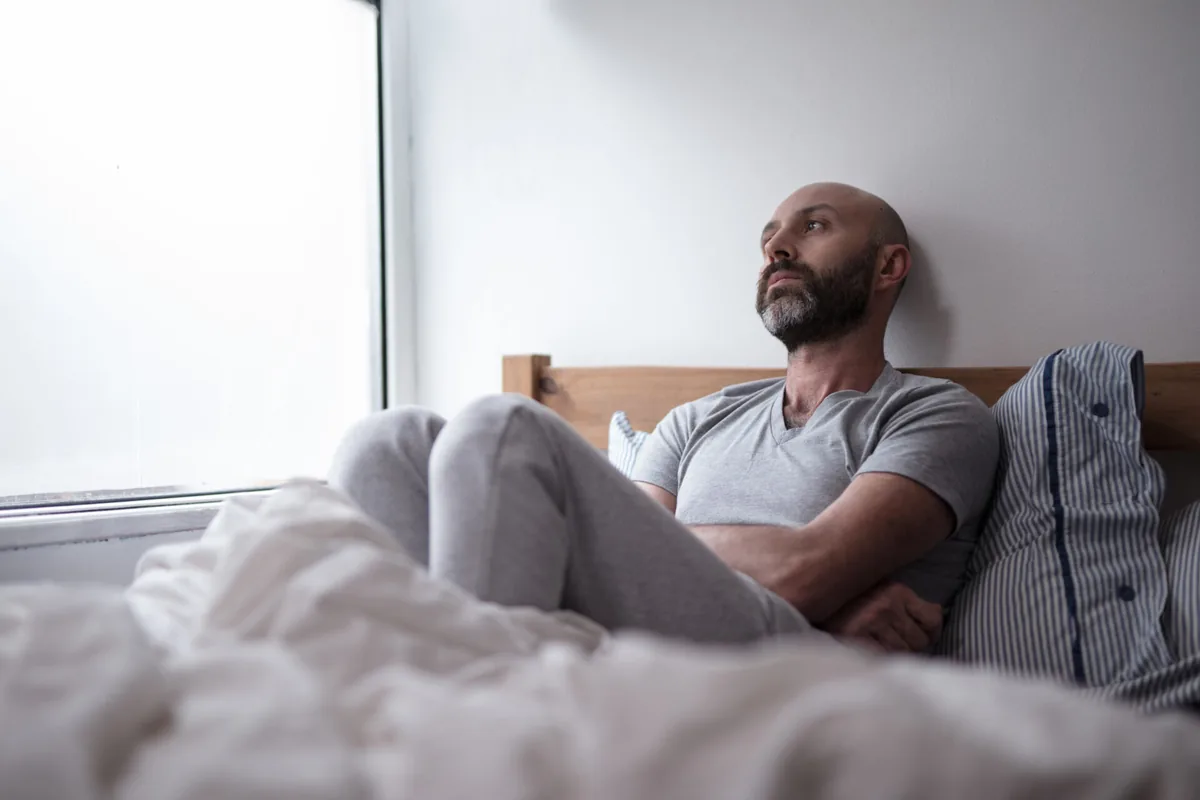 A man takes a quiet pause on a sofa at home.
