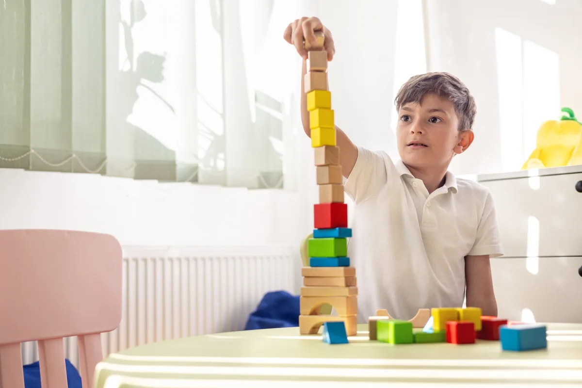 A child carefully builds a tower with colorful blocks.