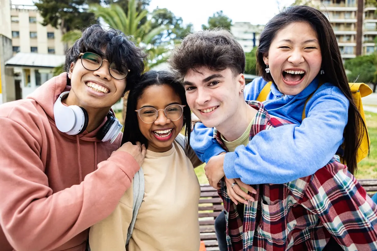 Four friends smile together outdoors.