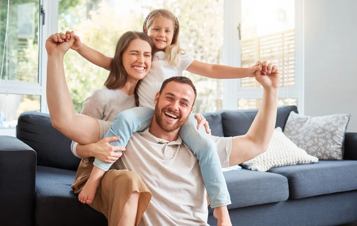 A father and children enjoy playing together on a sofa.