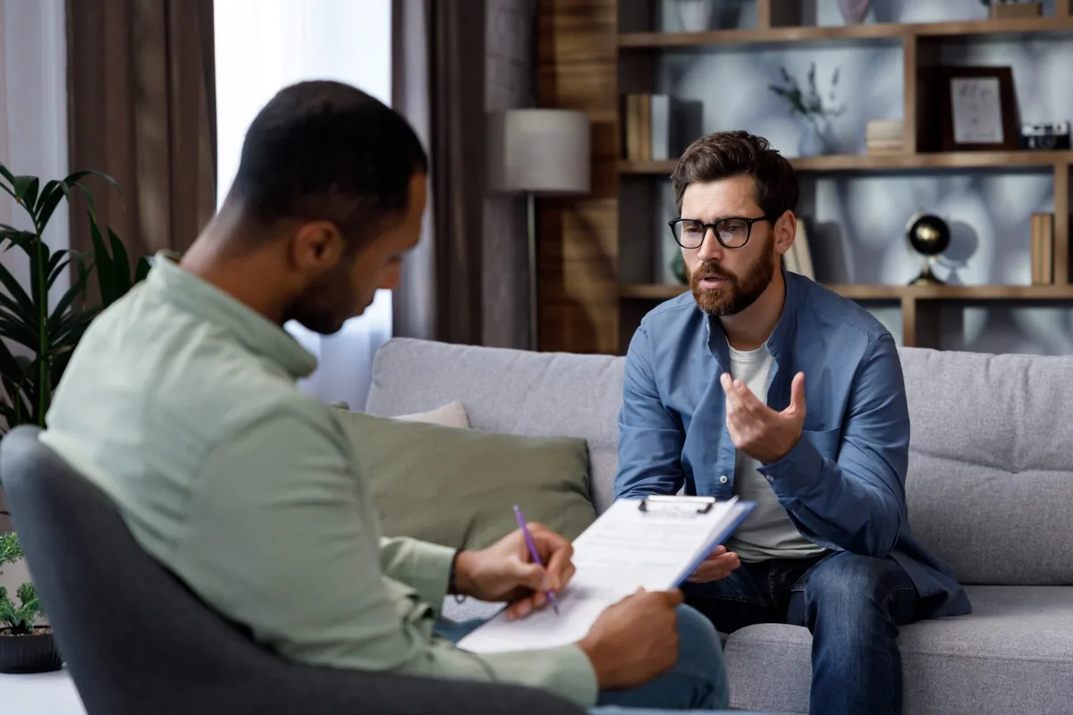 A man speaks with a counselor in a comfortable room.