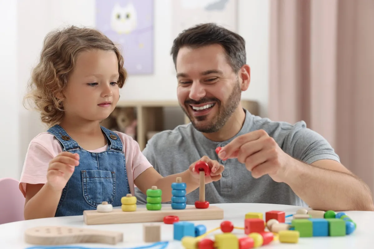 A father and young child build together with colorful blocks.