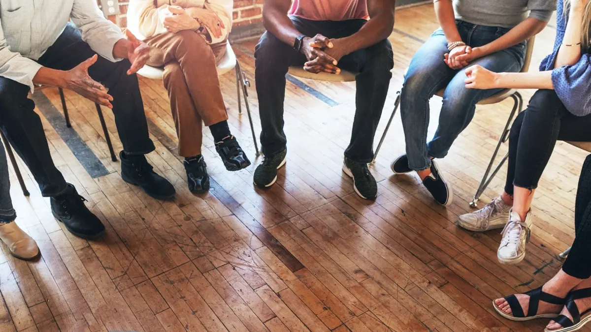 Adults sit in a circle during a support group discussion.