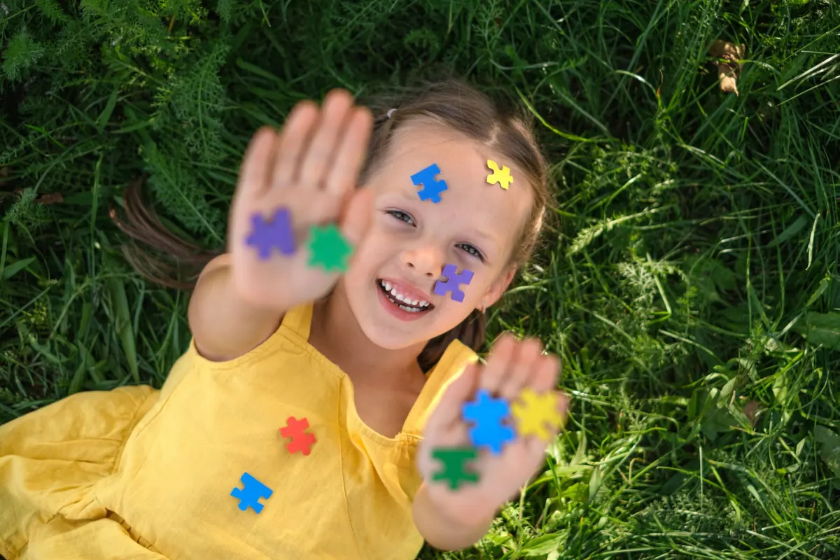 A child smiles while showing hands covered in colorful paint.