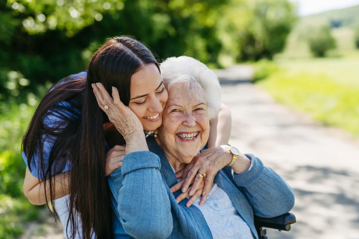 An older woman and a younger relative share a close embrace.