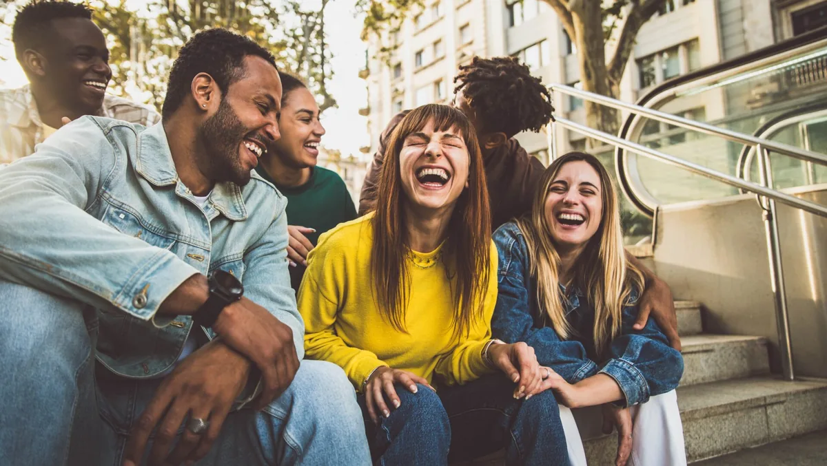 Friends laugh together while sitting outdoors.