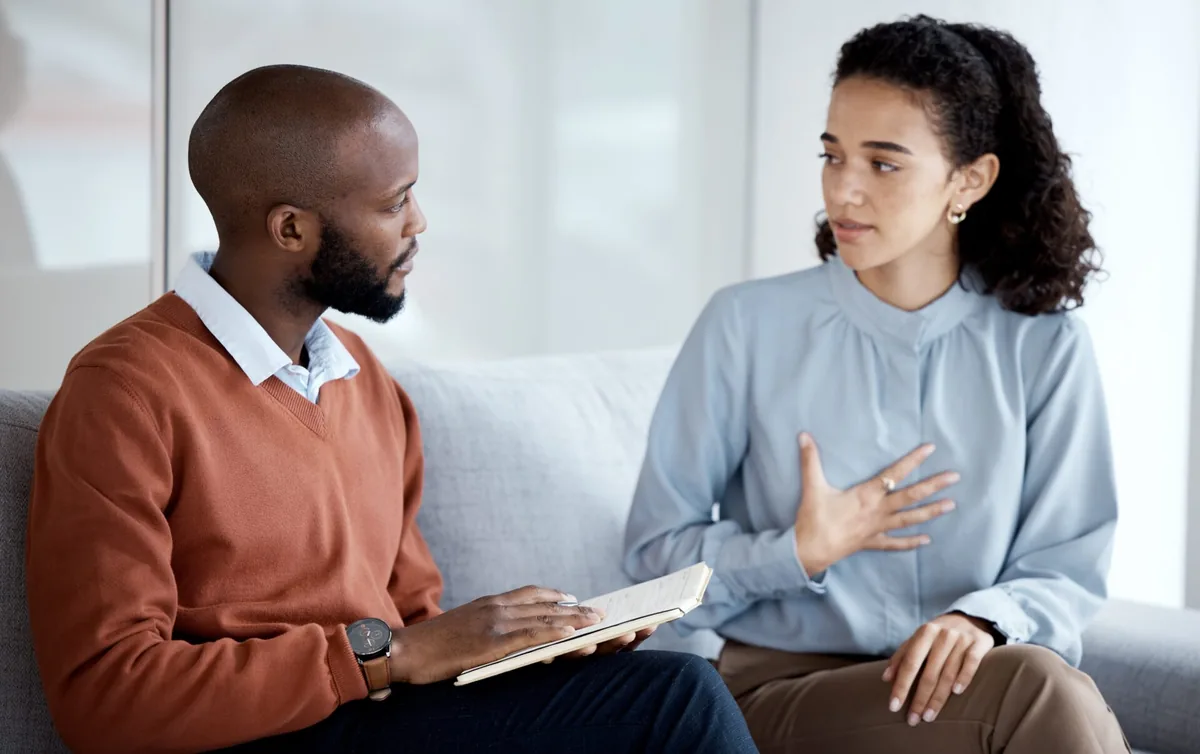 Two men talk together in a bright counseling room.