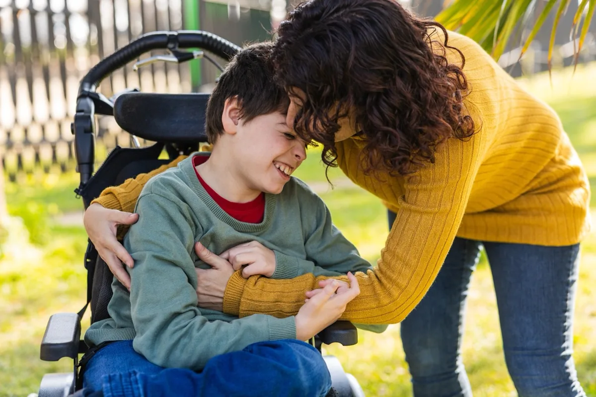 A parent helps a child with an activity at a table outdoors.