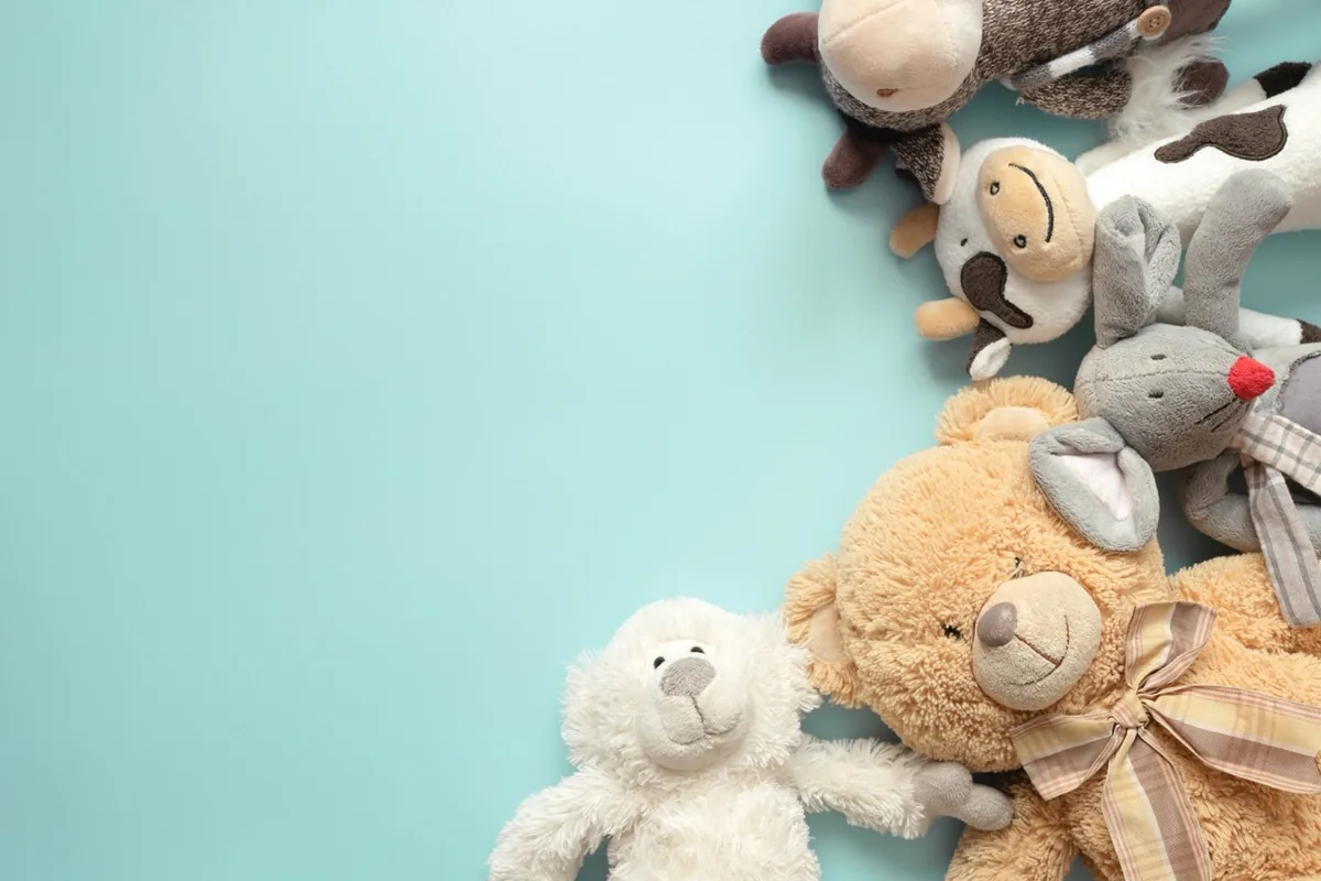 Soft toys lie beside one another on a pale blue surface.