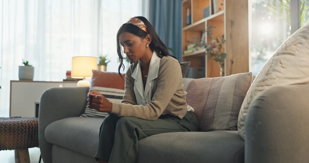A woman works on a laptop while sitting on a sofa.