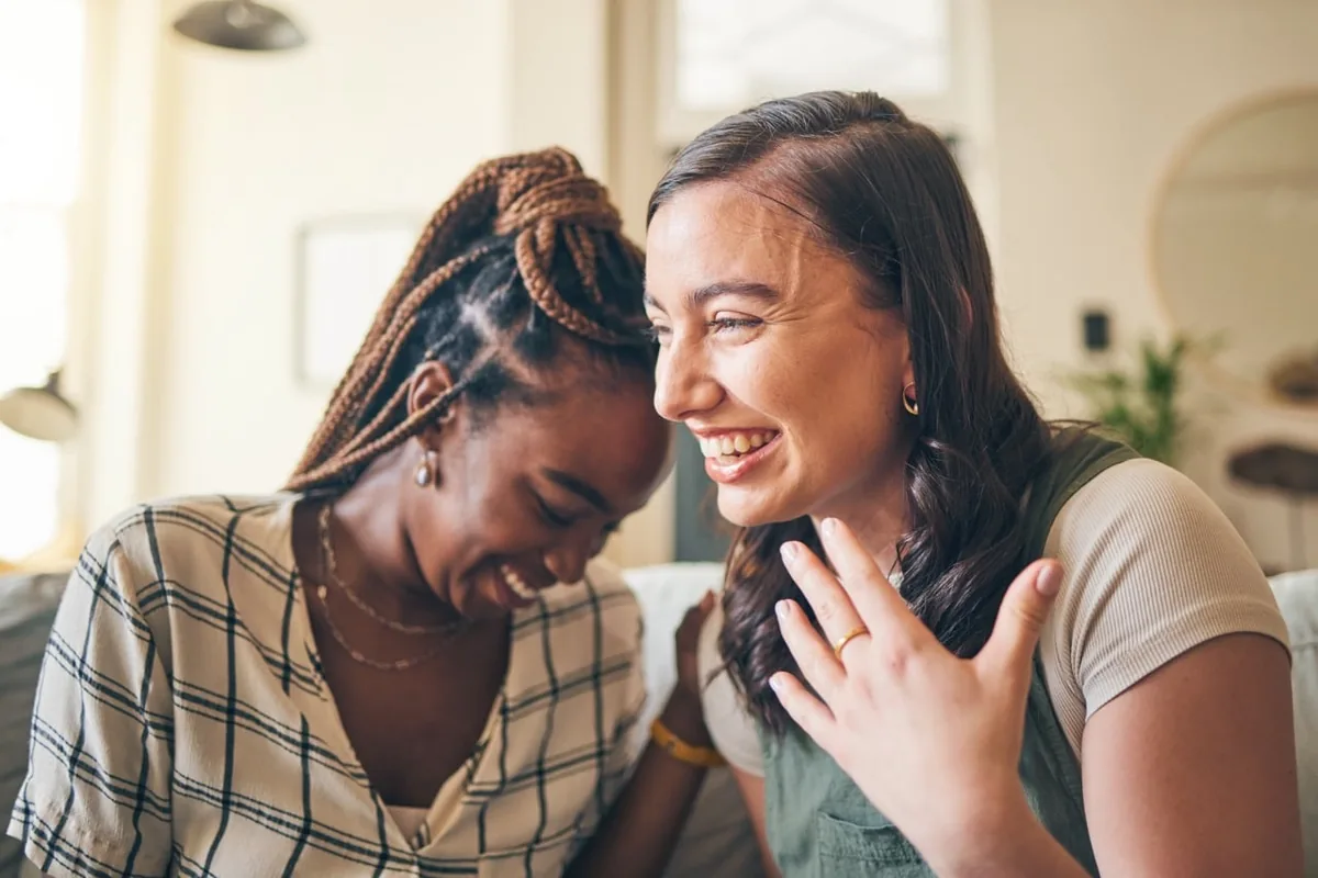 Two women rest their heads close together and smile.