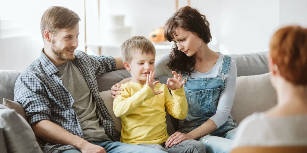 Parents and a young child spend time together on a sofa.