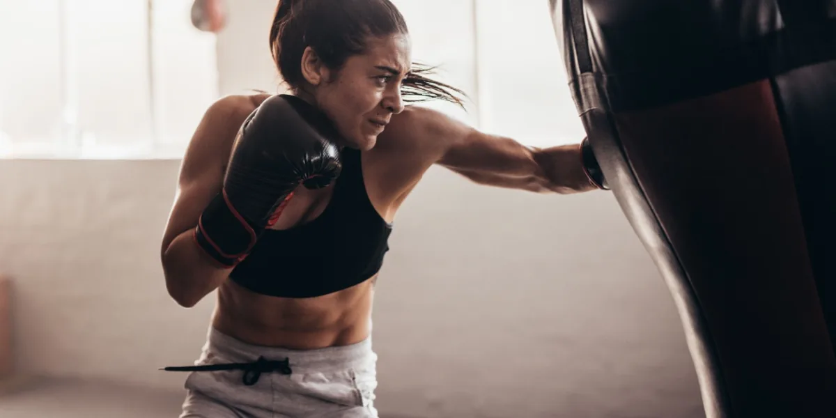 A woman practices boxing with a punching bag.