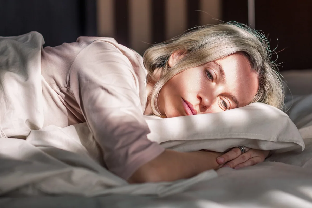 A woman rests on her side in bed.