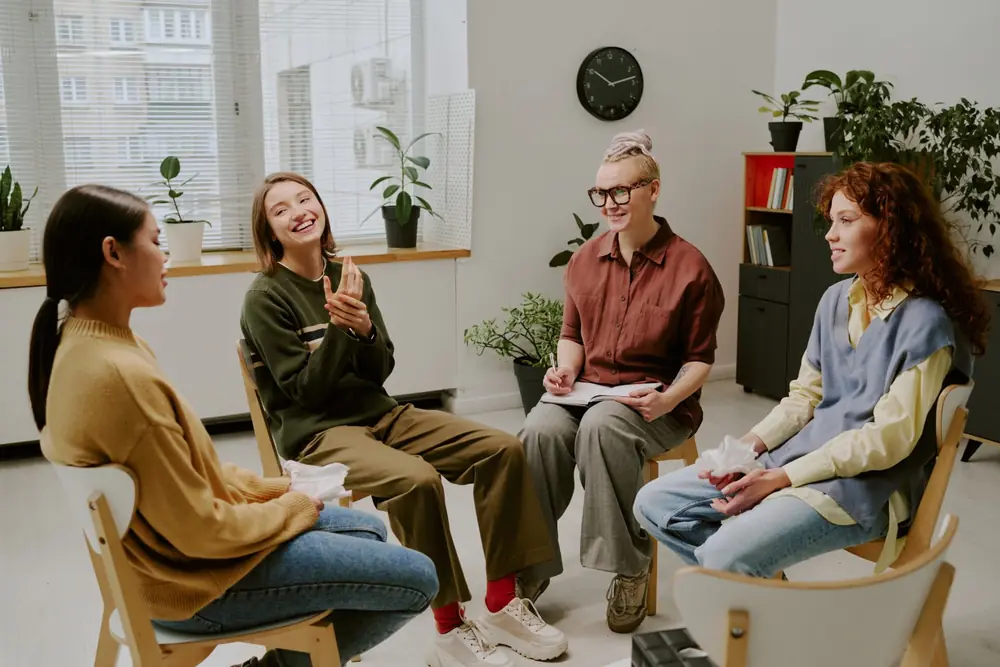 A group of adults talks together in a comfortable counseling room.