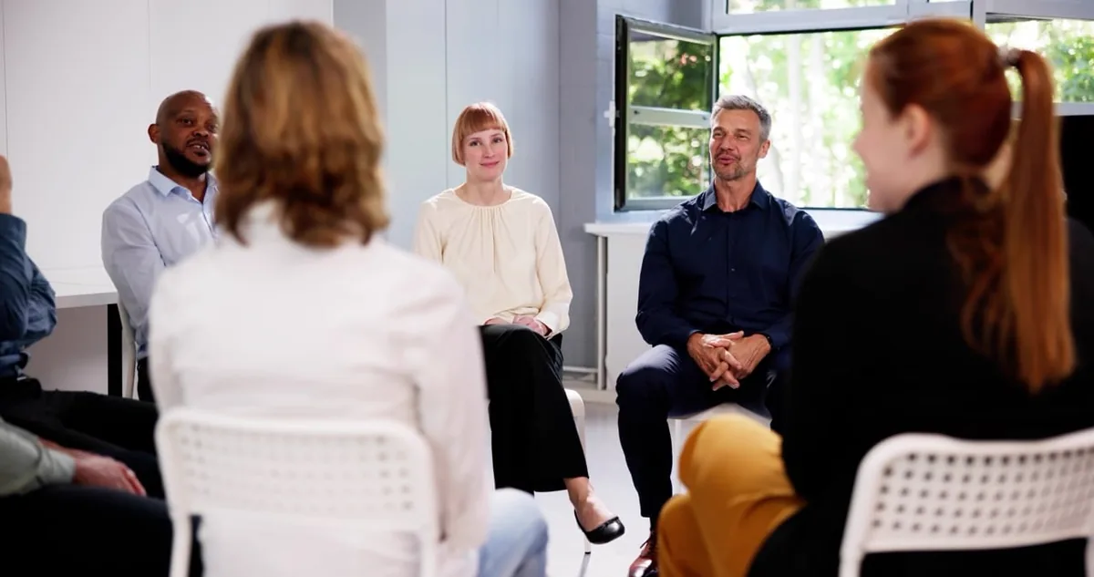 Adults sit together in a circle during a counseling session.