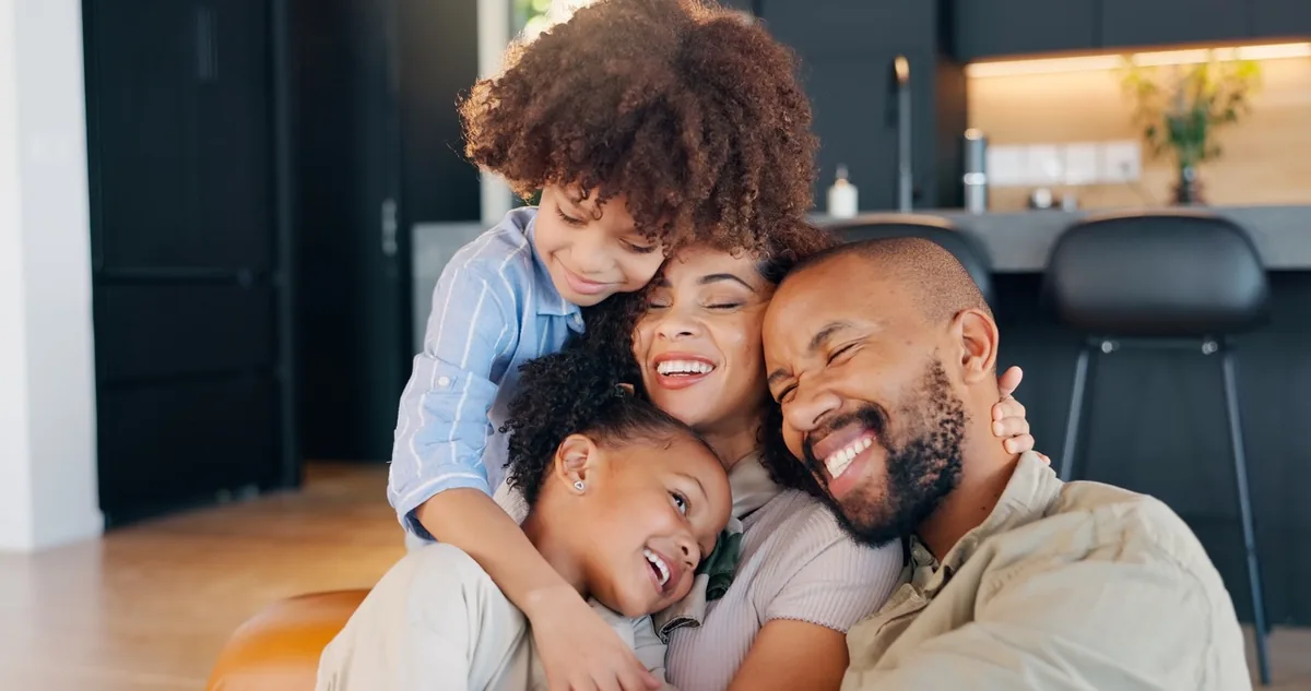 A family shares a cheerful close embrace at home.