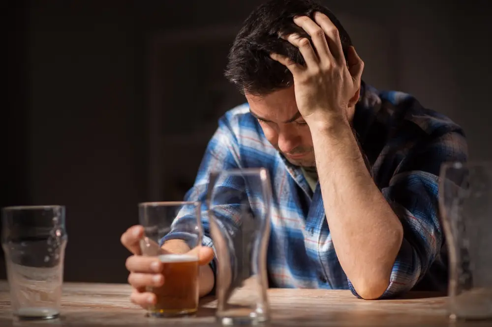 A man sits at a table with his head resting in one hand.
