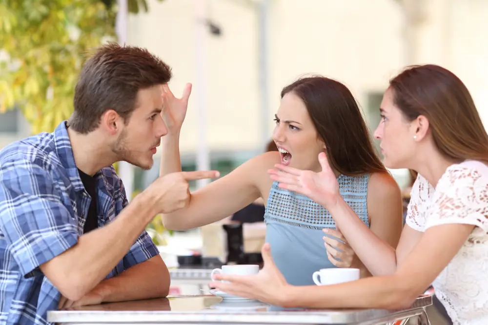 Three adults have a conversation around a table.