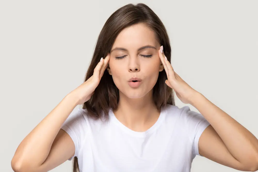 A woman rests her fingers near her temples.