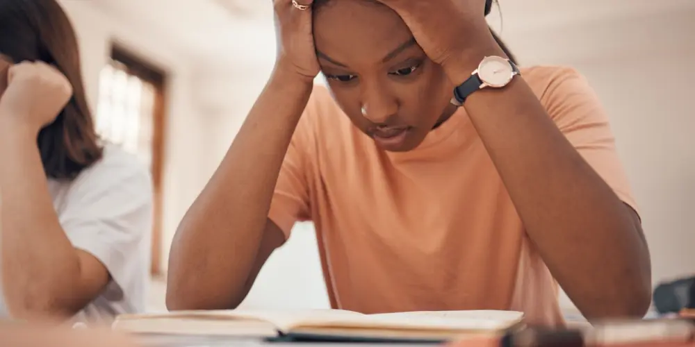 A young adult looks down at a table.