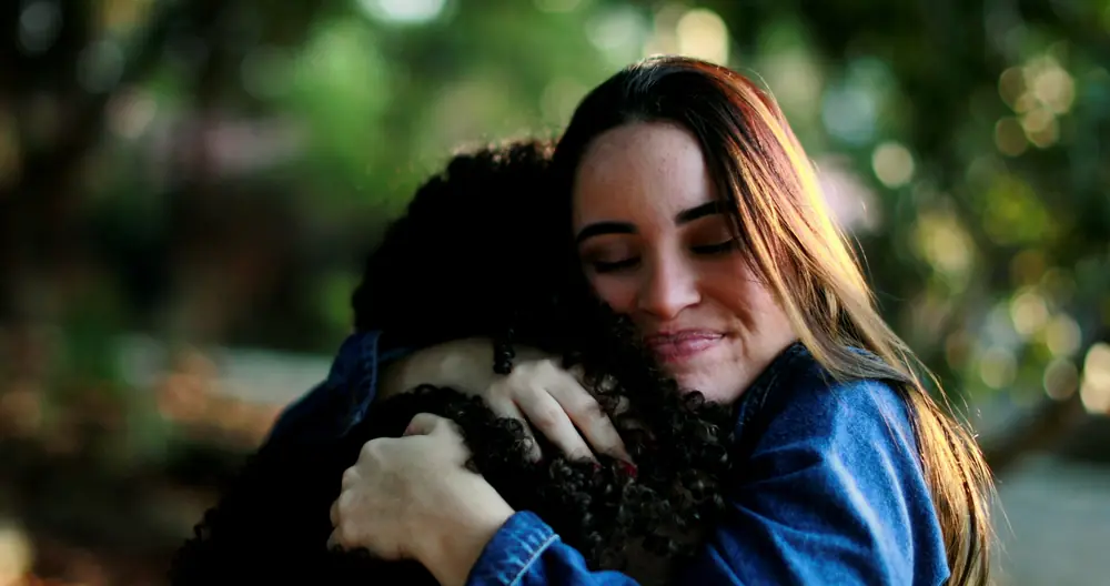 A woman hugs a pet while relaxing at home.
