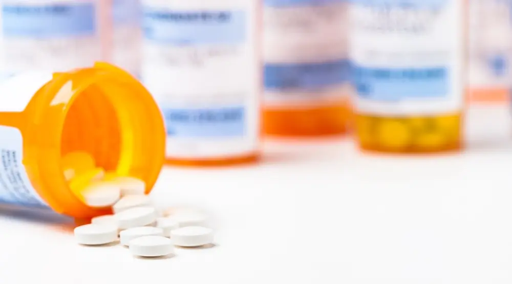 Prescription tablets beside medication containers.