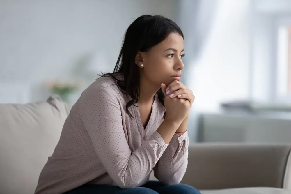A woman looks thoughtfully to one side in a quiet room.