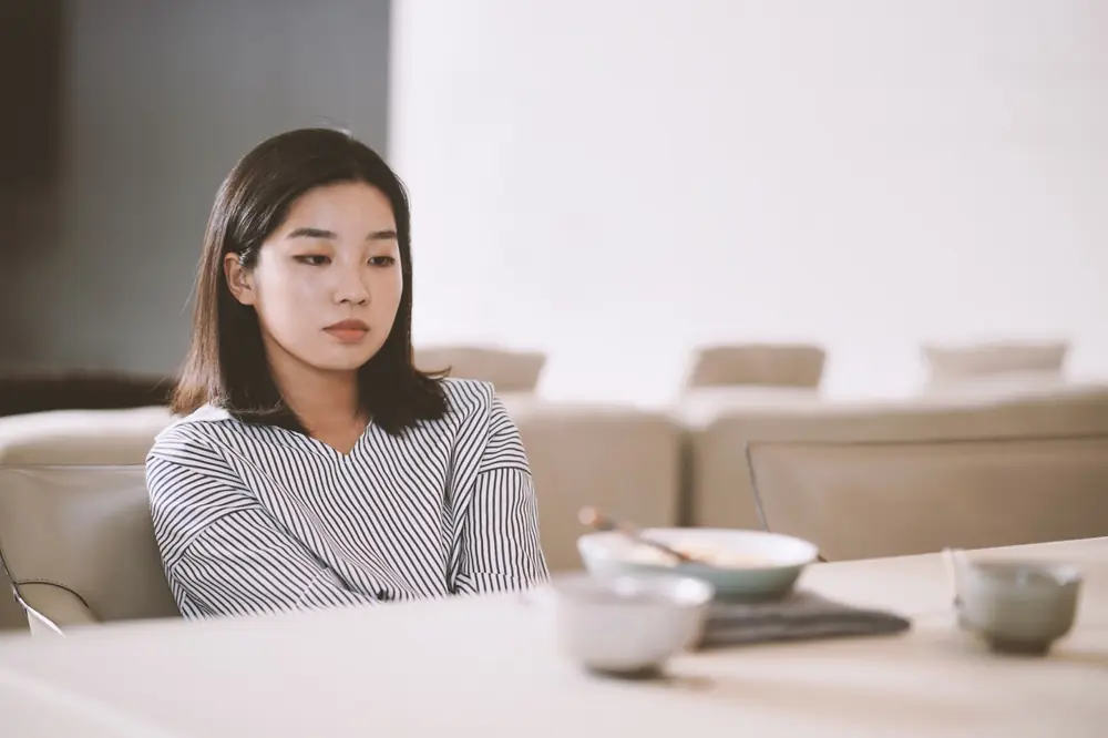 A woman sits at a table with a bowl.