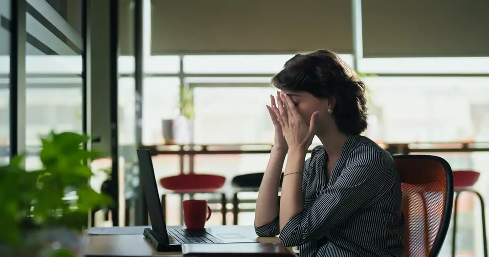 A woman sits at a table beside a window.