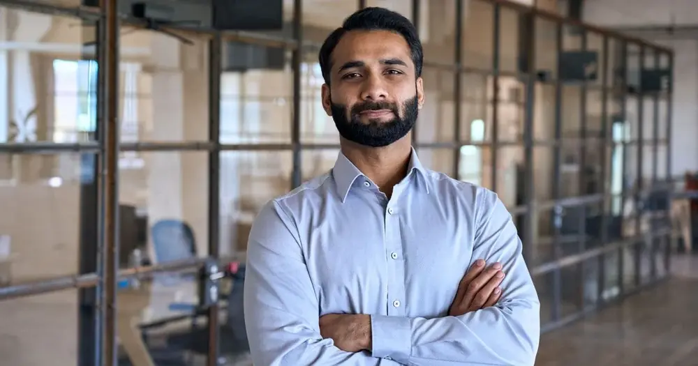A man in a blue shirt stands indoors.